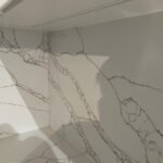 Угловая столешница и фартук из кварцевого агломерата изготовлено в правила камня