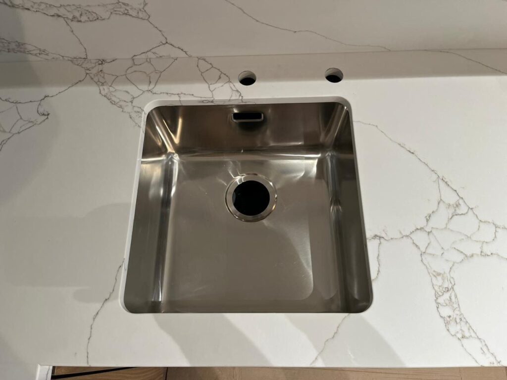 Угловая столешница и фартук из кварцевого агломерата изготовлено в правила камня