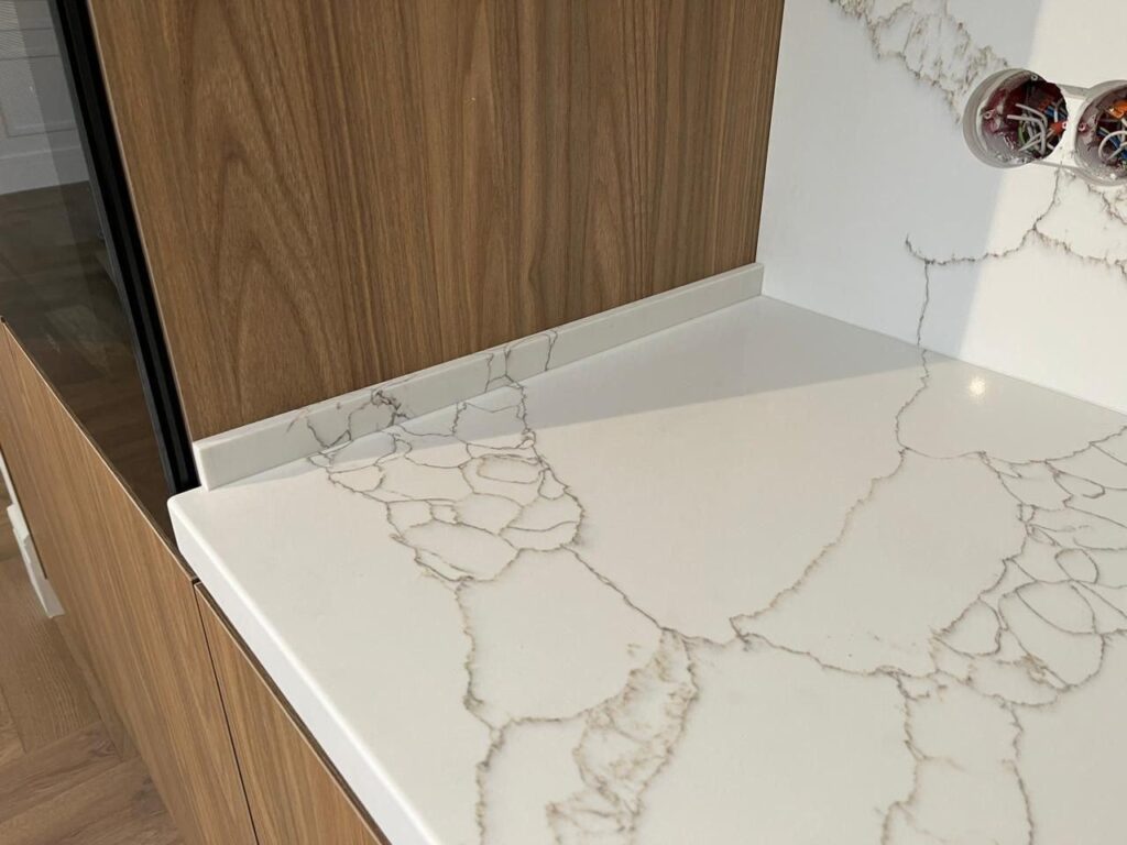 Угловая столешница и фартук из кварцевого агломерата изготовлено в правила камня