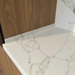 Угловая столешница и фартук из кварцевого агломерата изготовлено в правила камня