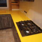 Желтая угловая столешница и мойка из искусственного камня изготовлено в правила камня