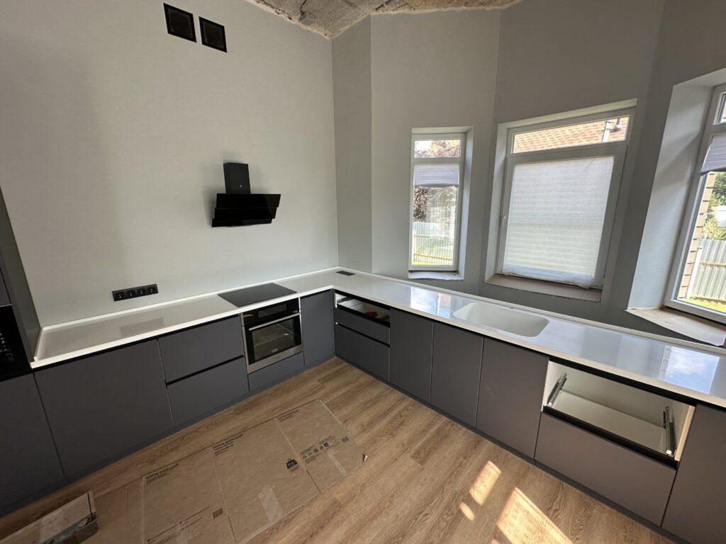 Бесшовная угловая столешница с мойкой и пристенным плинтусом на кухню из искусственного камня изготовлено в правила камня