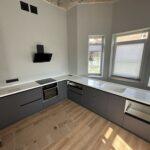 Бесшовная угловая столешница с мойкой и пристенным плинтусом на кухню из искусственного камня изготовлено в правила камня