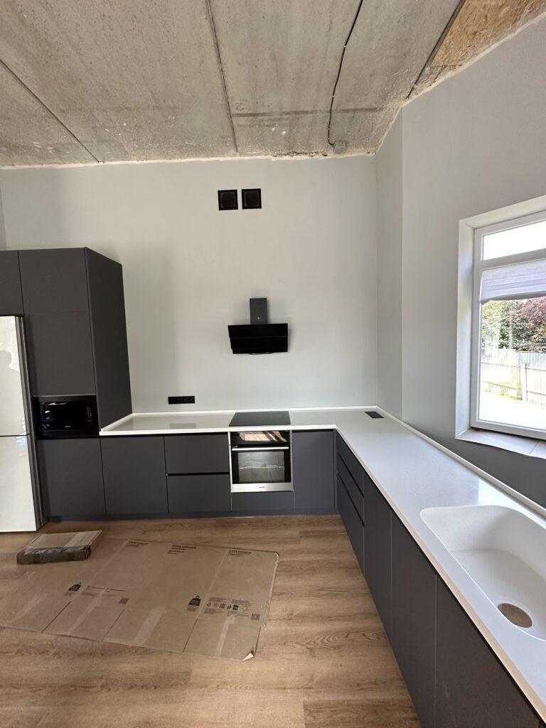 Бесшовная угловая столешница с мойкой и пристенным плинтусом на кухню из искусственного камня изготовлено в правила камня