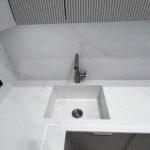 Кухонная столешница, мойка, стеновая панель и барная стойка из белого кварцевого агломерата изготовлено в правила камня