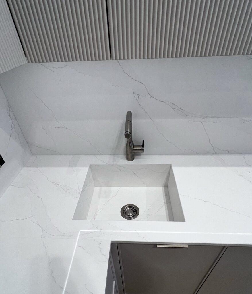 Кухонная столешница, мойка, стеновая панель и барная стойка из белого кварцевого агломерата изготовлено в правила камня