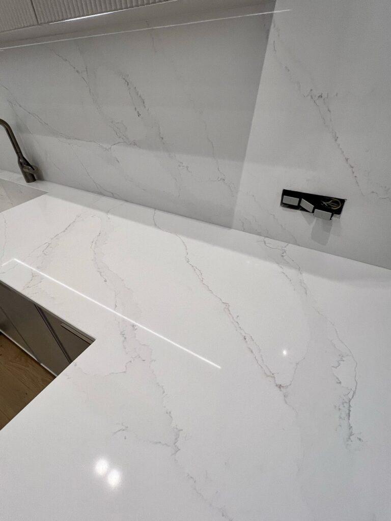 Кухонная столешница, мойка, стеновая панель и барная стойка из белого кварцевого агломерата изготовлено в правила камня